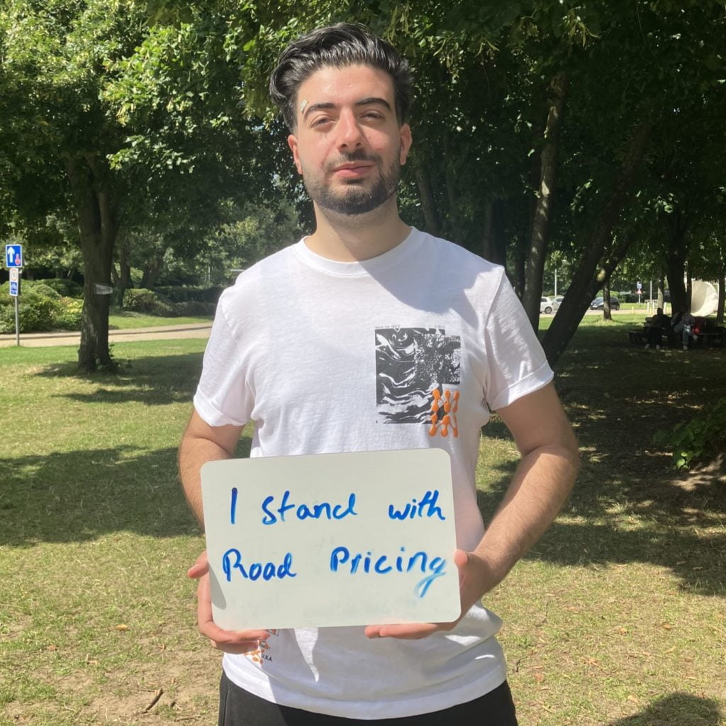 Man holds handwritten sign: "I stand with road pricing"
