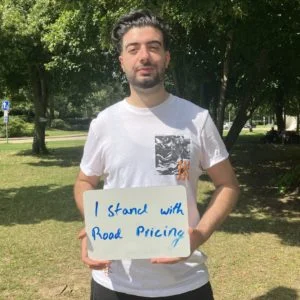 Man holds handwritten sign: "I stand with road pricing"